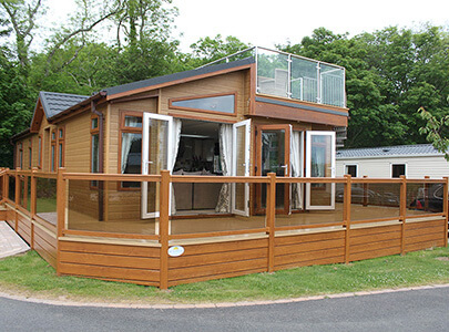 AB Sundecks Picket Glass, Decking and Steps surrounding a Lodge with a balcony on top with Steel Top Glass and stairs
